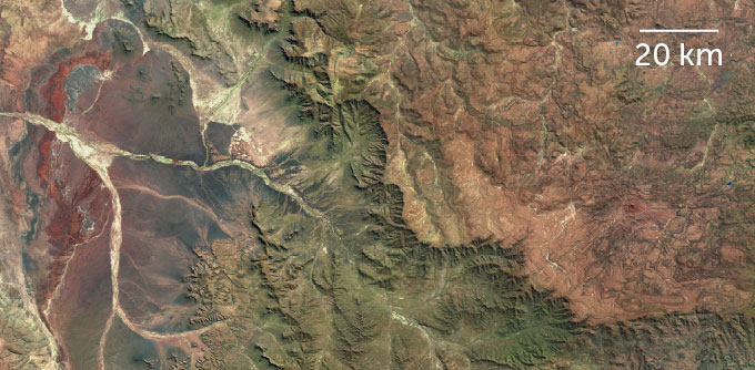 Brown mountains stand in the background, with golden grass covered foothills in the foreground.